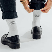 Person wearing black shoes and white socks with 'Call Me Daddy' text, standing on a light background.